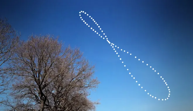 Die Sonne, ein Jahr lang jeweils zur gleichen Uhrzeit fotografiert: Sie zeichnet ein Analemma in Form einer Acht über kahlen Bäumen und blauem Himmel.